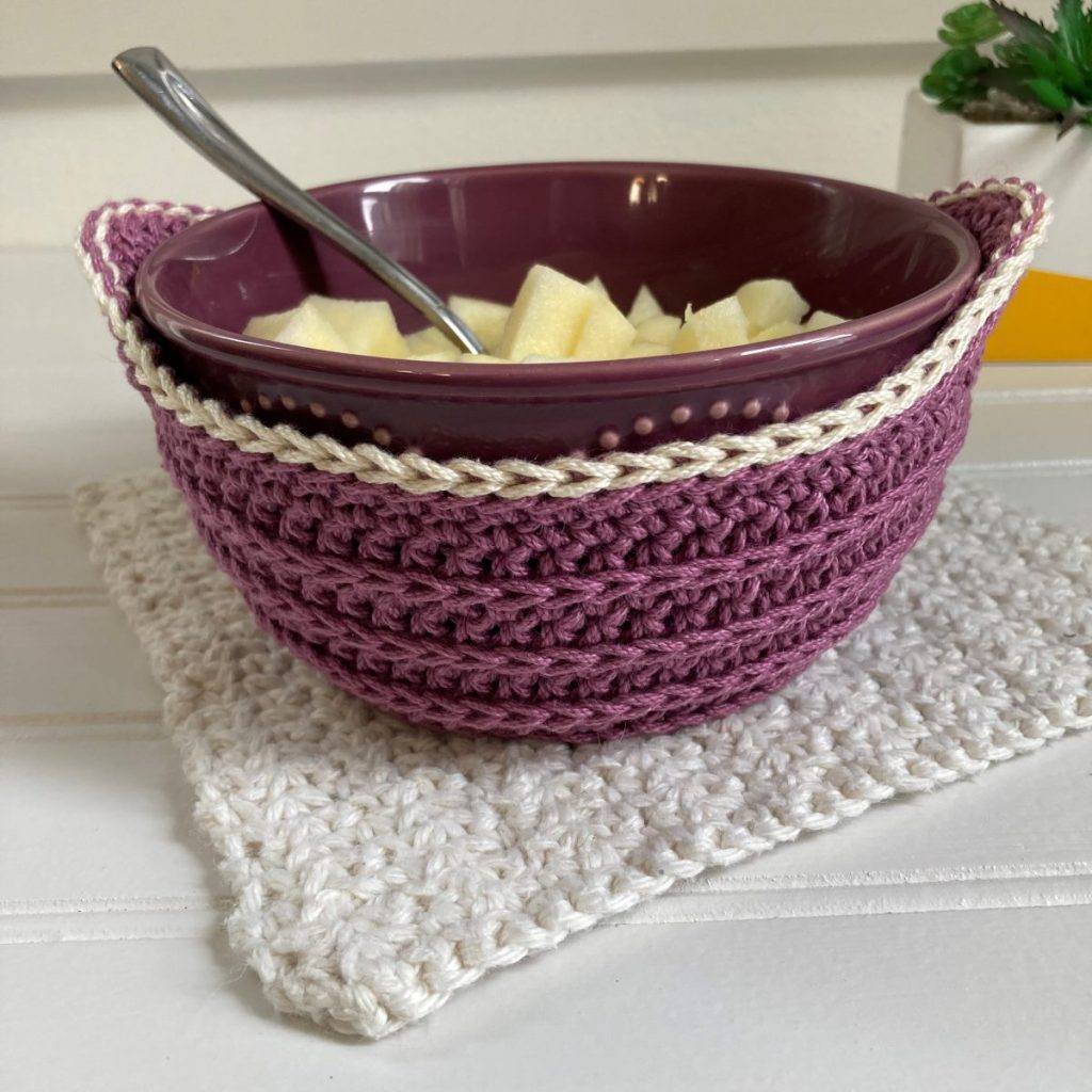 purple crochet bowl cozy with apple over oatmeal